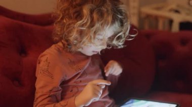Küçük bir kız karanlık bir odada ekranın ışığıyla oyun oynar ya da tablet bilgisayar izler. 