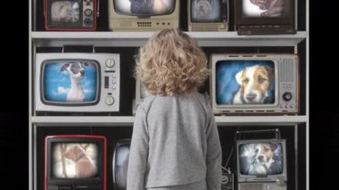 Genç kız ekranda köpeklerle televizyon seyrediyor.