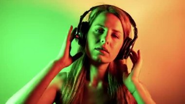 Müzik dinlemek için kulaklıkları olan havalı bayan dansçı ve renkli disko ışıkları.