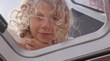 Pencereden bakan küçük bir kız yazın Yunan 'da bir yat kapağı açıyor. 