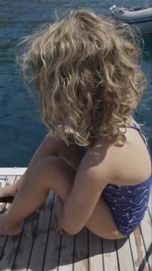 Yunanca bir yatın yüzme güvertesinde küçük bir kız yazın dikey