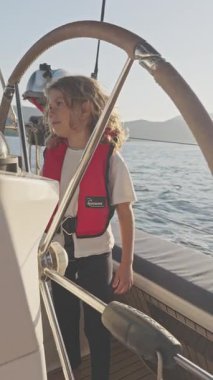 Yunanca bir yatın dümenindeki küçük kız yazın dikey olarak