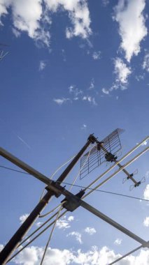 Gökyüzü ve bulutların zaman çizelgesi. Ön planda dikey televizyon antenleri var.