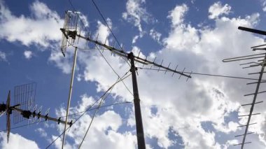 Gökyüzünün zaman çizelgesi ve ön planda televizyon anteni olan bulutlar. 