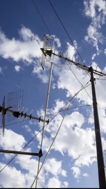 Gökyüzü ve bulutların zaman çizelgesi. Ön planda dikey televizyon antenleri var.