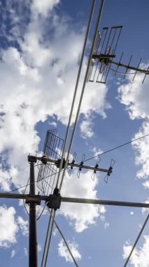 Gökyüzü ve bulutların zaman çizelgesi. Ön planda dikey televizyon antenleri var.