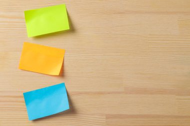 Multicolored different notes or sticky post-it on wooden office table background .mockup