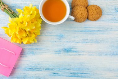 Bir buket nergis, mavi arka planda bahar çiçekleri. Çay ve kurabiye. en üstteki görünüm.