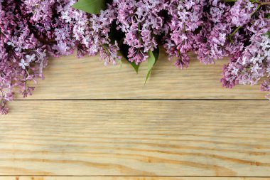Doğal ahşap bir masada bahar leylak dalları çerçevesi. Üst Manzara. bir yazıt için yer.