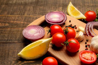 Sebzeler, bitkiler ve baharatlar. Kahverengi masada salata hazırlama malzemeleri var.