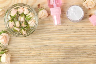 Losyon, yüz ve vücut kremi, ahşap bir masada gül özü, kişisel bakım için kozmetik ürünler, spa tedavileri. en üstteki görünüm.