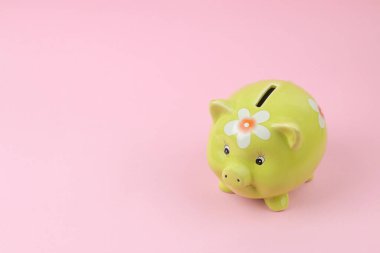 Pembe arka planda yeşil domuz kumbarası, para tasarrufu konsepti.