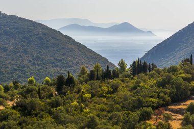 Akdeniz manzaralı, iki tepe arasında deniz manzaralı. Denizde iki ada daha görülebilir. Yunan adaları