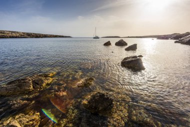 Akşamları kayalık sahil, deniz ve yelkenli ile manzara. Sicilya