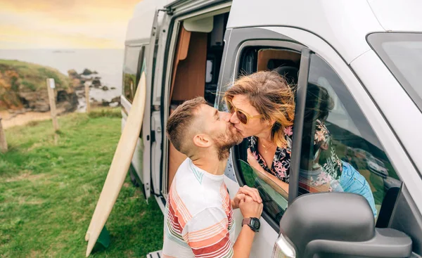 一对年轻夫妇在旅行中通过野营车的窗户接吻 — 图库照片
