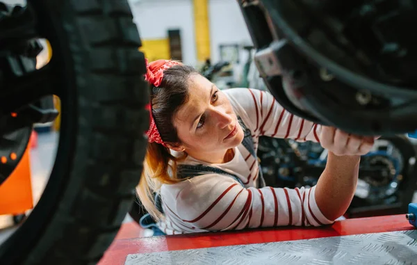 工場でオートバイのエンジンをチェックする集中整備士の女性の肖像 — ストック写真