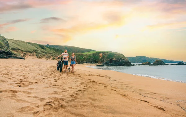 stock image Couple with a fat bike taking a walk on the beach with their dog