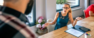 Surprised young woman arguing with her colleague for problems in coworking. Conflict at work concept.