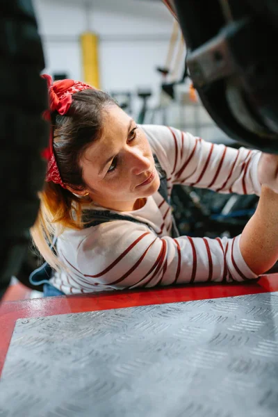 工場でオートバイのエンジンをチェックする集中整備士の女性の肖像 — ストック写真