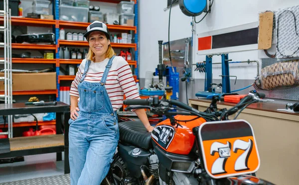 Счастливая Женщина Механик Кепке Смотрит Камеру Стоящую Перед Мотоциклом Заводе — стоковое фото