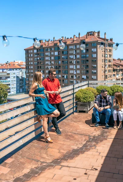 在夏天的一天 一对年轻夫妇在屋顶上和朋友聊天 背景是城市 — 图库照片