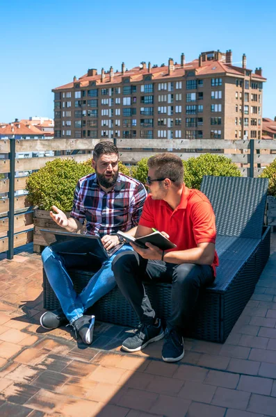 在阳光灿烂的日子里 有胡子的男人与相貌像平板电脑的女同事坐在办公室的屋顶上聊天 — 图库照片