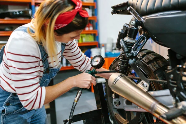 オートバイのタイヤ空気圧を工場でチェックする機械的な女性 — ストック写真