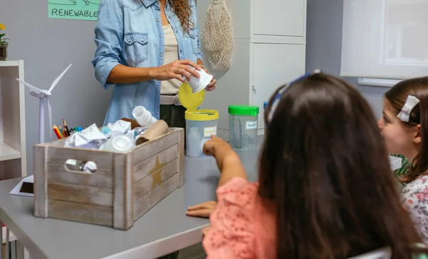 Chica Apuntando Caja Reciclaje Mientras Profesora Sosteniendo Paquete Plástico Aula —  Fotos de Stock