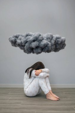 Zihinsel bozukluğu ve intihar düşünceleri olan tanınmayan bir kadın odasında kara bir fırtına bulutunun altında oturup ağlıyor. Olumsuz duygular ve kötü duygular konsepti.