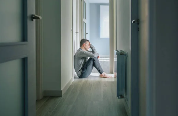 精神疾患と自殺念慮を持つ絶望的な男は 精神保健センターの床に座っ手で頭を保持します — ストック写真
