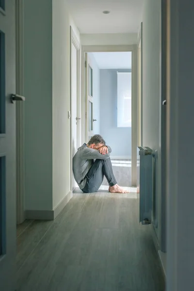 无法辨认的精神障碍和自杀念头的男人坐在走廊的地板上哭泣 — 图库照片