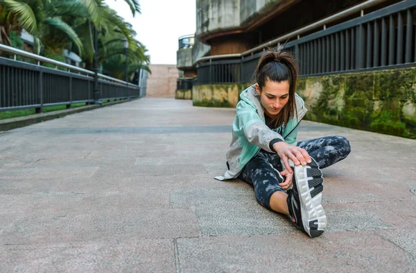 Kasabadaki Eğitimden Önce Esmer Kadın Koşucu Yerde Oturmuş Bacağını Esnetiyor — Stok fotoğraf