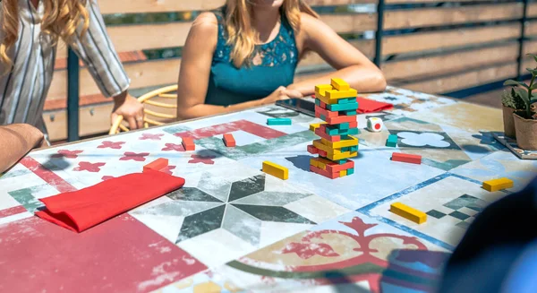 夏のパーティーで屋上でゲームをプレイしている認識できない人々とタイルのテーブルの上にJengaタワー — ストック写真