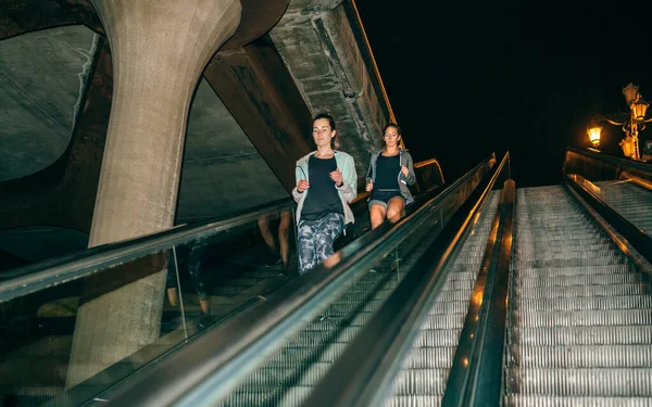 Zwei Junge Freundinnen Trainieren Nachts Rolltreppe Der Stadt Herunterzufahren — Stockfoto