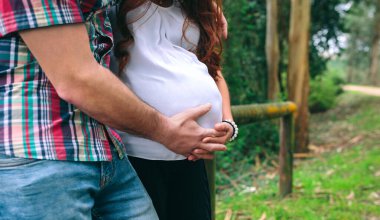 Tanınmaz haldeki Latin kadın hamile ve eşi doğada karnını tutuyor.