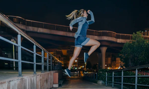 若い金髪の女性は夜空の都市で心臓のトレーニングエクササイズでジャンプします 正しいコピースペース — ストック写真