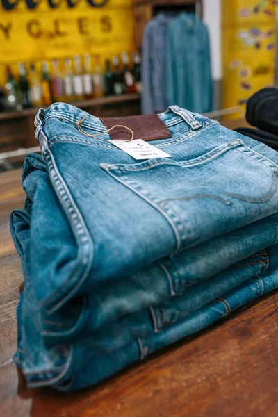 ヴィンテージの服店のカウンターの上に青いジーンズパンツの近くにスタック 工業的なスタイルで店舗で販売する準備ができているオーガナイズされた服 アパレル小規模ビジネスコンセプト — ストック写真