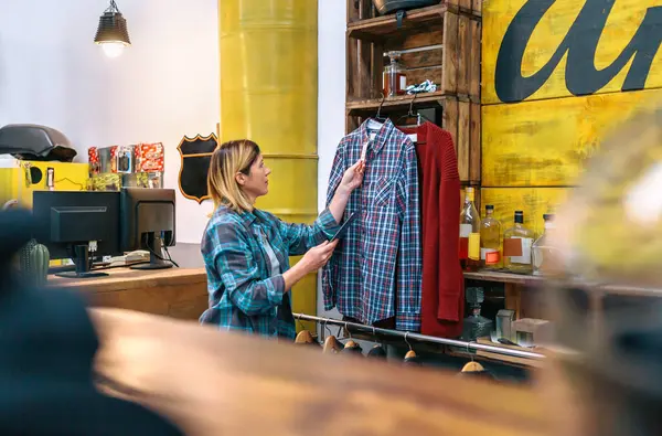 Sarışın Kadın Elinde Dijital Tablet Tutarken Eski Elbise Dükkanındaki Ekose — Stok fotoğraf