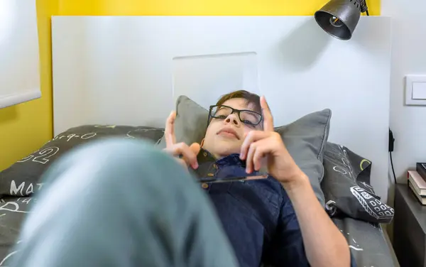 Entspannter Junge Mit Futuristischer Transparenter Tablette Die Über Seinem Bett Stockbild