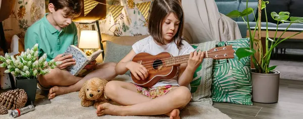 Banner Little Girl Playing Ukulele While Boy Reading Book Handmade Stock Picture