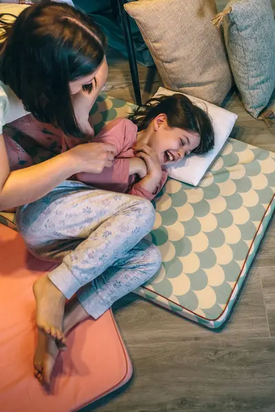 Mutlu anne, gece pijama partisinde hasırların üzerine yatıp gülerken ve bağırırken küçük kızını gıdıklıyor. Kadın ve kadın ergenler evde oynayıp eğleniyorlar. Aile hafta sonu aktiviteleri konsepti