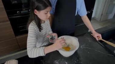Genç bir kız birlikte ev yapımı pasta hazırlıyor, bir kasede malzemeleri karıştırıyor ve yemek pişirme deneyimini neşe ve takım çalışmasıyla paylaşıyor. Erkek ve kız kardeş modern mutfakta kek pişiriyorlar.