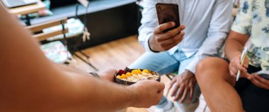 Mango, muz, ahududu, tahıl gevreği ve müsli 'den yapılmış sağlıklı kahvaltı kasesi sunan tanınmamış şef pankartı blogculara ve nüfuzlu kişilere yemek pişirme yüksek sınıfında akıllı telefonlarla fotoğraf çekiyor.