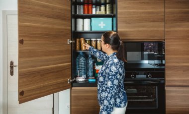 Bilinmeyen bir kadın elektrik kesintisi için uyarı, öngörü ve kendi kendine yetme stratejisi hazırlıyor. Kadın, dolapta depolanan 72 saatlik hayatta kalma kitine kurabiye paketi ekliyor. Acil yemek kileri..