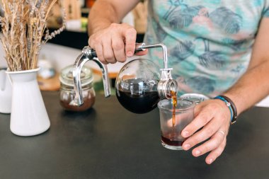 Tanımlanamayan kahve ustalıkla Japon kahve makinesinden kahve doldurup bardağa doldurarak özel kahve hazırlama sanatını sergiliyor..