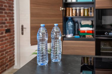 Dolabın önünde su şişeleri, yiyecek, içecek, gerekli malzemeler ve mutfakta giysiler var. Hükümetin acil durum veya savaşa hazırlık konusundaki tavsiyelerine göre depolanan hayatta kalma kileri.