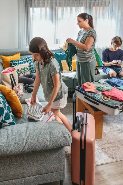 Anne ve kızı bavulları katlıyor ve paketliyor. Bu arada genç oğlu da sıcak oturma odasındaki kanepede oturup yaz tatiline hazırlanıyor. Aile yolculuk için çantaları hazırlıyor..