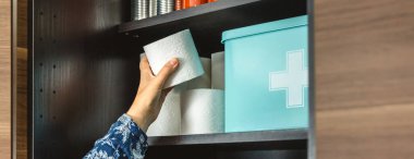 Mutfaktaki acil durum yemek kilerine tuvalet kağıdı dolduran tanınmamış kadın eli pankartı potansiyel felaketlere karşı hazırlanıyor. 72 saat hayatta kalma çantası konsepti. Uyanık, öngörülü ve kendi kendine yeten..