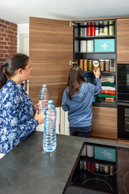 Aile 72 saat hayatta kalma kiti hazırlıyor. Mutfak kilerinde yiyecek, su ve yiyecek kıtlığı için ilk yardım çantasıyla fıstık saklayan bir kız. Öngörü ve kendi kendine yetme stratejisi.