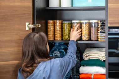 Fıstık konteynırını acil durum yiyecek deposunda saklayan tanınmamış bir kız. Su, kurabiye, makarna, fasulye, bakla, tahıl ve su ile 72 saat hayatta kalma kiti felaket veya yiyecek kıtlığı için hazır..